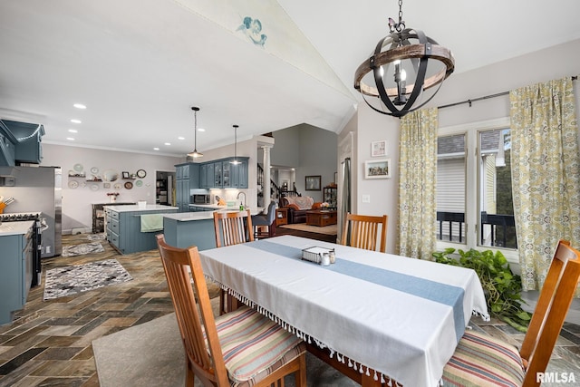 dining area featuring a chandelier, crown molding, lofted ceiling, and sink