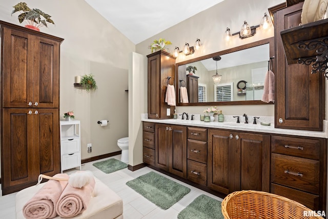 bathroom with tile patterned flooring, vanity, toilet, and vaulted ceiling