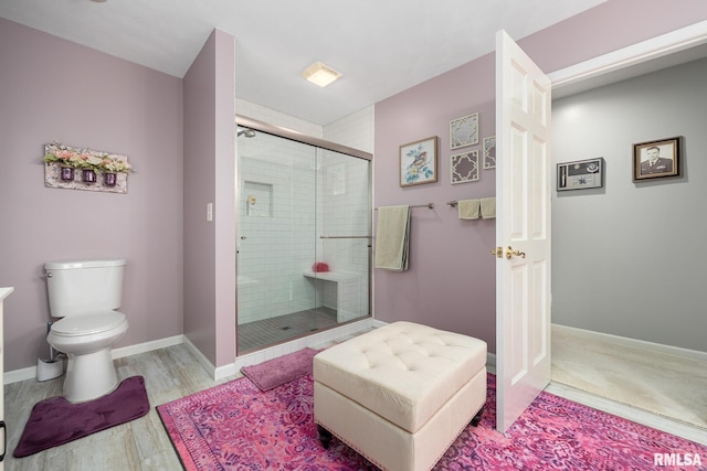 bathroom featuring toilet, a shower with door, and hardwood / wood-style flooring