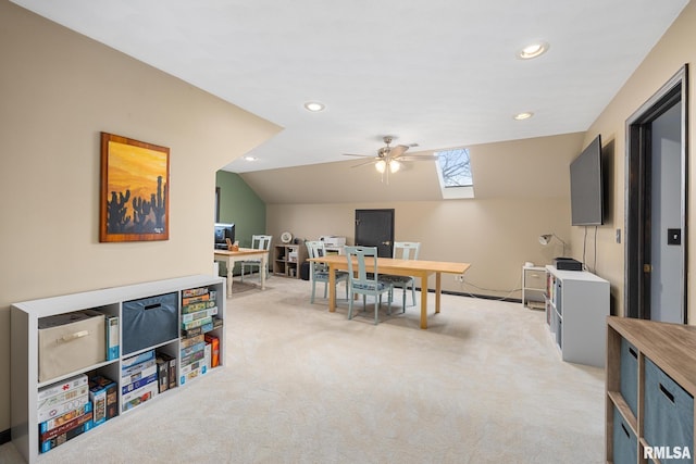 carpeted home office with ceiling fan and lofted ceiling with skylight