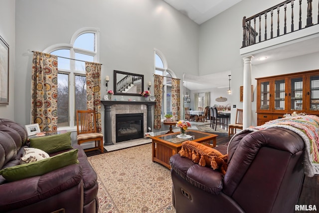 living room with a fireplace, a high ceiling, hardwood / wood-style flooring, and ornate columns