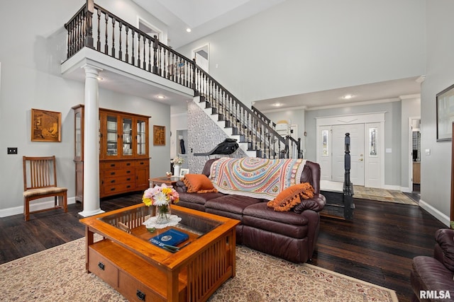 living room with dark hardwood / wood-style flooring, a towering ceiling, and ornate columns