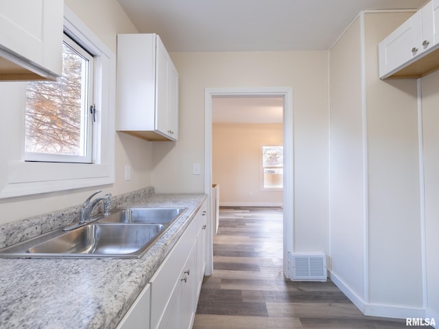 kitchen with dark hardwood / wood-style floors, white cabinetry, and sink