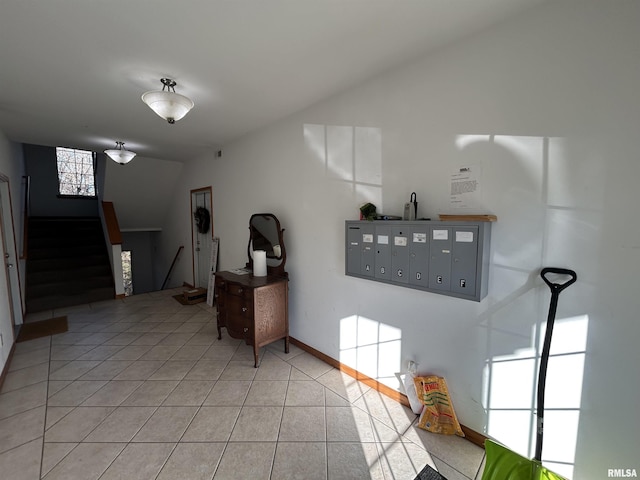 interior space featuring light tile patterned floors, lofted ceiling, and a mail area