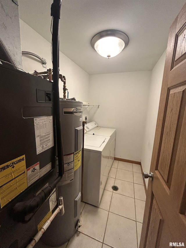 clothes washing area featuring washing machine and dryer, light tile patterned floors, and water heater