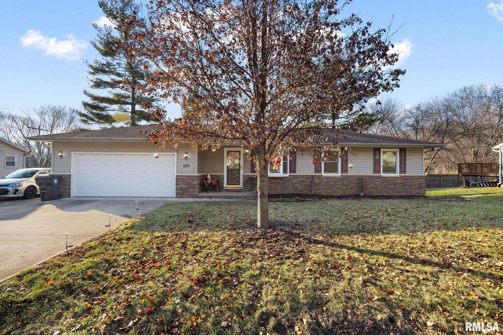 ranch-style house featuring a garage and a front lawn