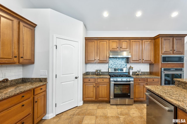 kitchen with decorative backsplash, appliances with stainless steel finishes, and dark stone counters