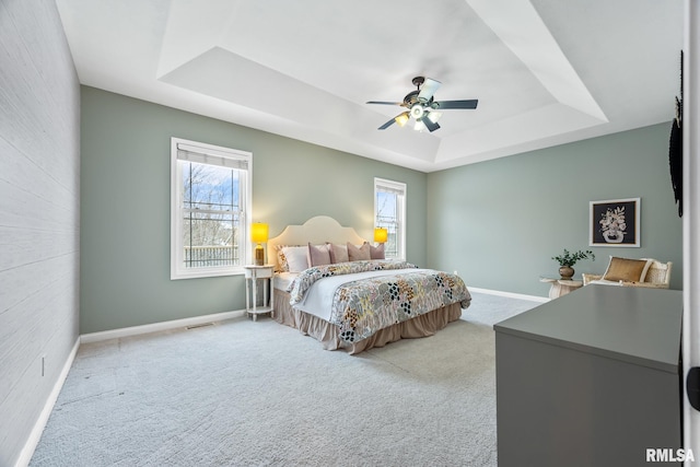 bedroom with light carpet, a raised ceiling, and ceiling fan