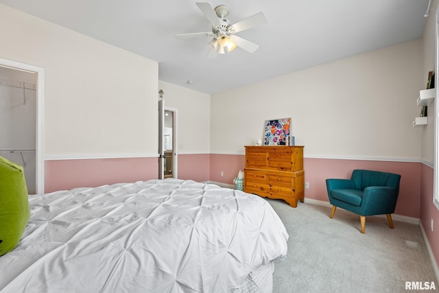 bedroom featuring light carpet, a walk in closet, a closet, and ceiling fan