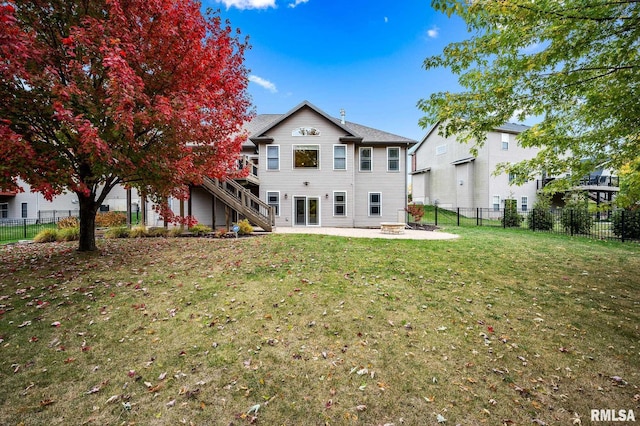 back of house with a wooden deck, a yard, and an outdoor fire pit