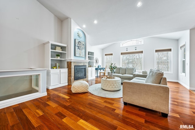 living room featuring a tile fireplace, wood-type flooring, and lofted ceiling