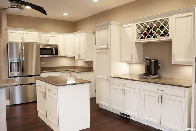 kitchen featuring dark hardwood / wood-style flooring, stainless steel appliances, ceiling fan, white cabinets, and a center island