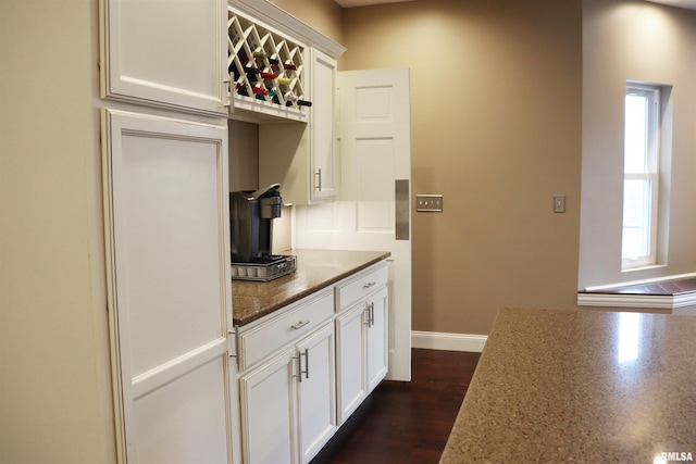 kitchen with white cabinets, dark wood-type flooring, and dark stone counters