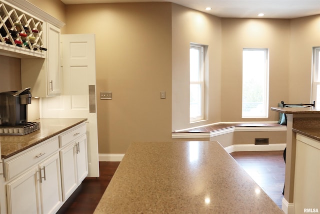 kitchen featuring dark hardwood / wood-style flooring, white cabinetry, and dark stone countertops