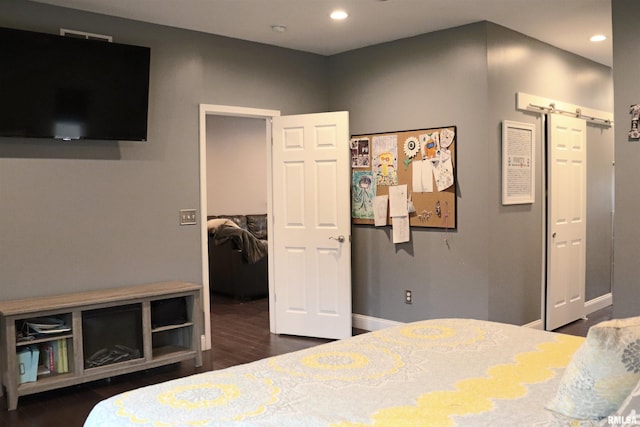 bedroom with a walk in closet and dark hardwood / wood-style floors