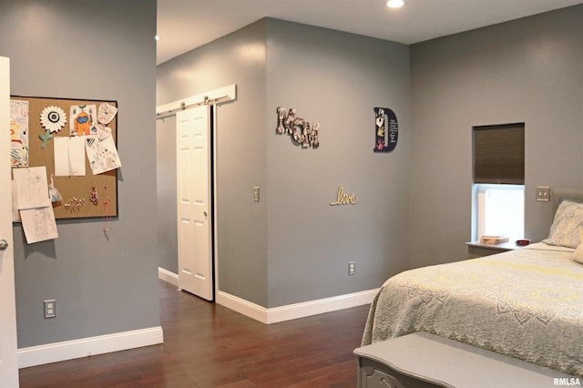 bedroom with a barn door, a closet, and dark hardwood / wood-style floors