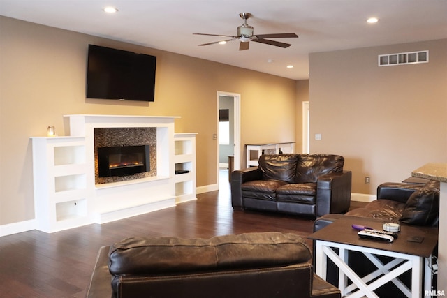 living room with built in shelves, dark hardwood / wood-style floors, and ceiling fan