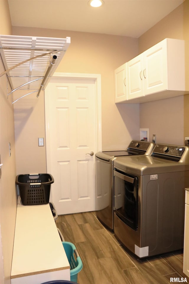 washroom featuring washer and dryer, cabinets, and wood-type flooring