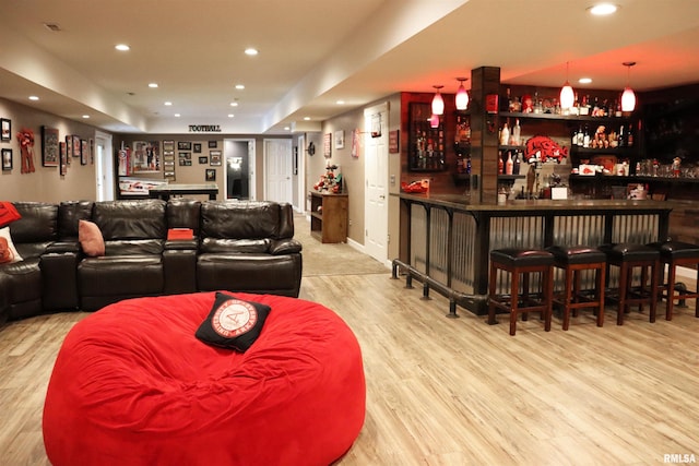 bar with light hardwood / wood-style floors and hanging light fixtures