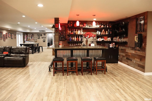 bar with decorative light fixtures and light wood-type flooring