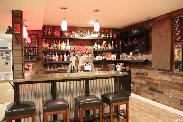 bar with light hardwood / wood-style flooring and pendant lighting