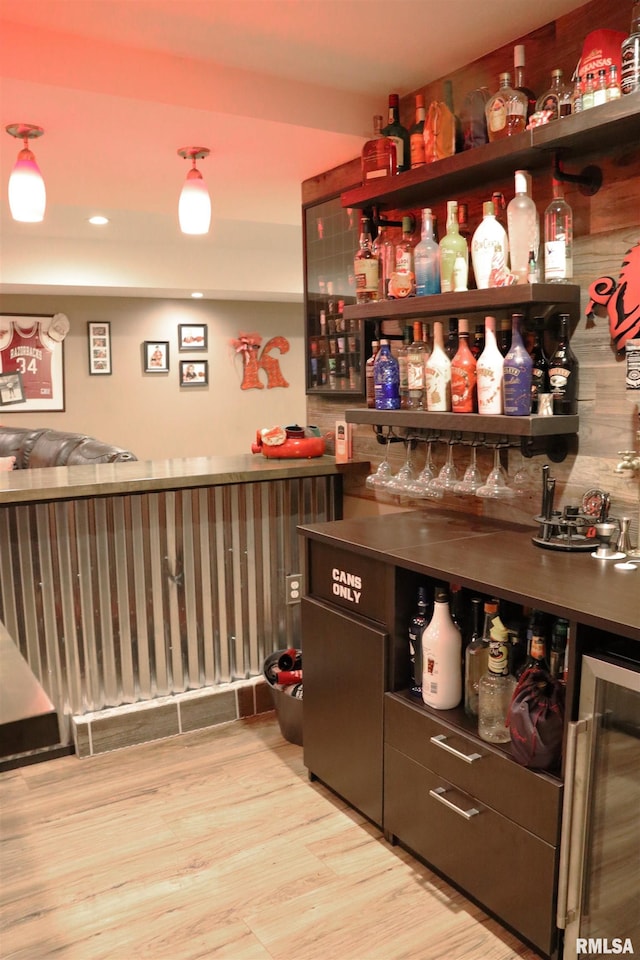 bar with wine cooler and light hardwood / wood-style flooring