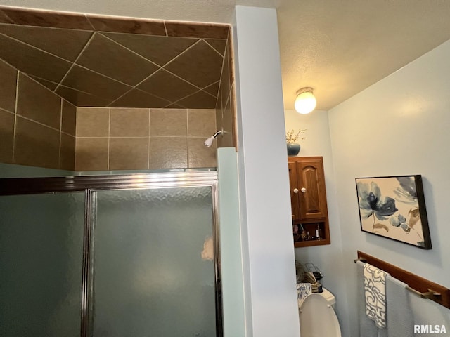 bathroom with toilet and a shower with door