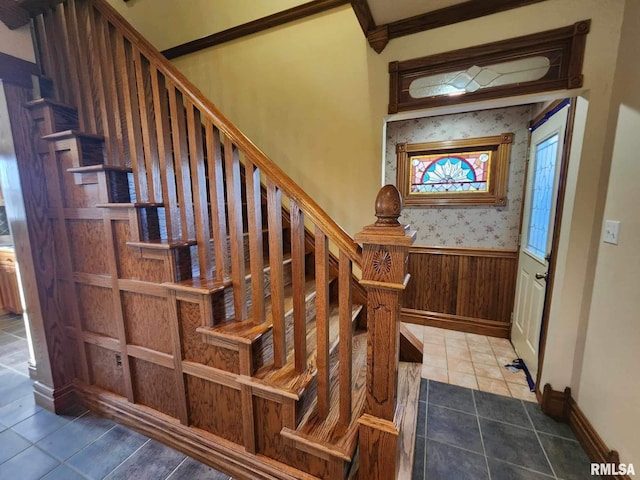 stairway featuring wood walls and ornamental molding