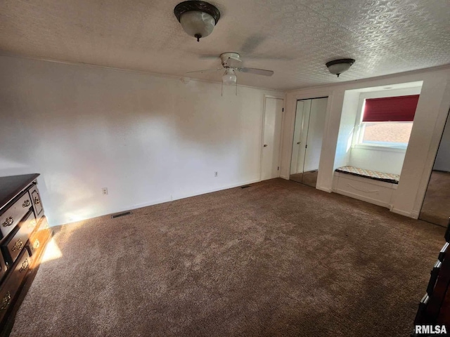 unfurnished bedroom with ceiling fan, carpet, and a textured ceiling