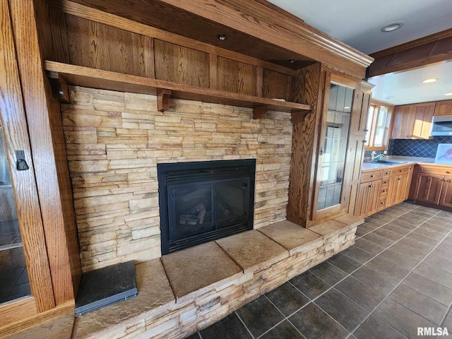 room details featuring decorative backsplash, a fireplace, and sink