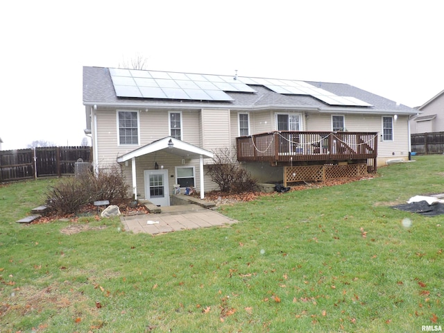 back of property with solar panels, a yard, and a deck