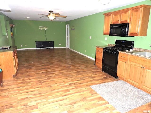 kitchen with ceiling fan, sink, black appliances, and light hardwood / wood-style floors