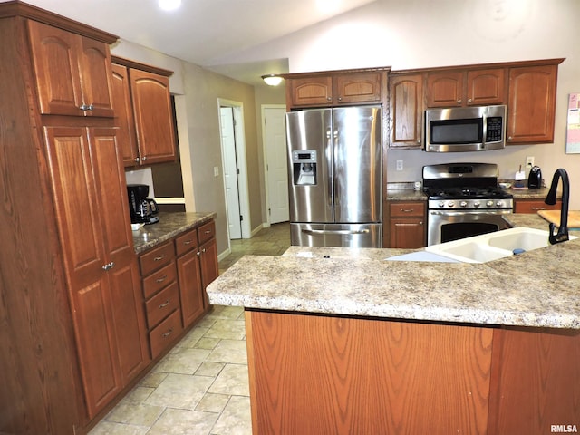 kitchen featuring light stone counters, sink, appliances with stainless steel finishes, and vaulted ceiling