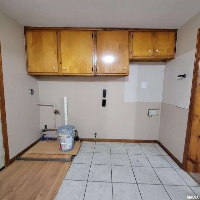 clothes washing area with light tile patterned flooring and cabinets