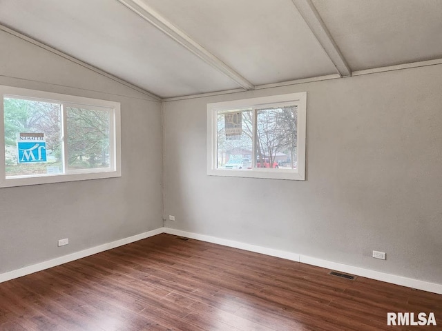 empty room featuring vaulted ceiling with beams and hardwood / wood-style floors