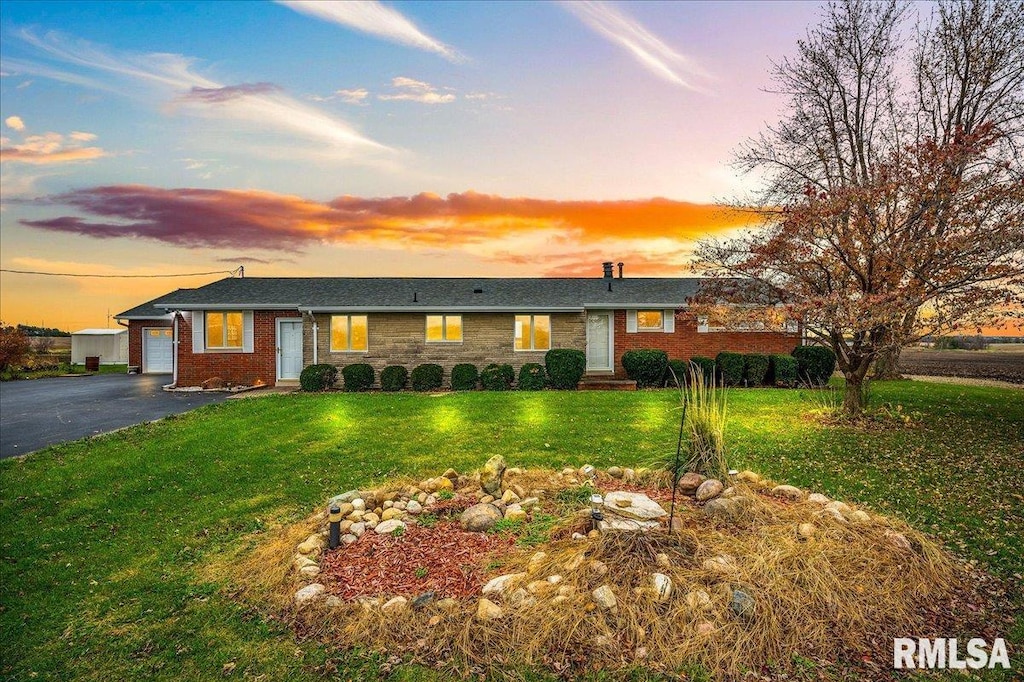 ranch-style house with a garage and a yard