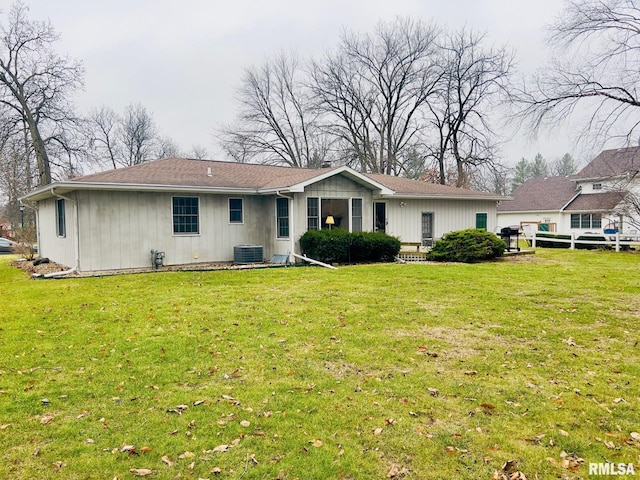 rear view of property featuring a lawn and central air condition unit