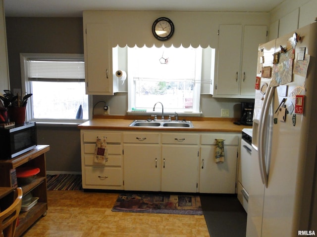 kitchen with white refrigerator with ice dispenser, white cabinets, a wealth of natural light, and sink