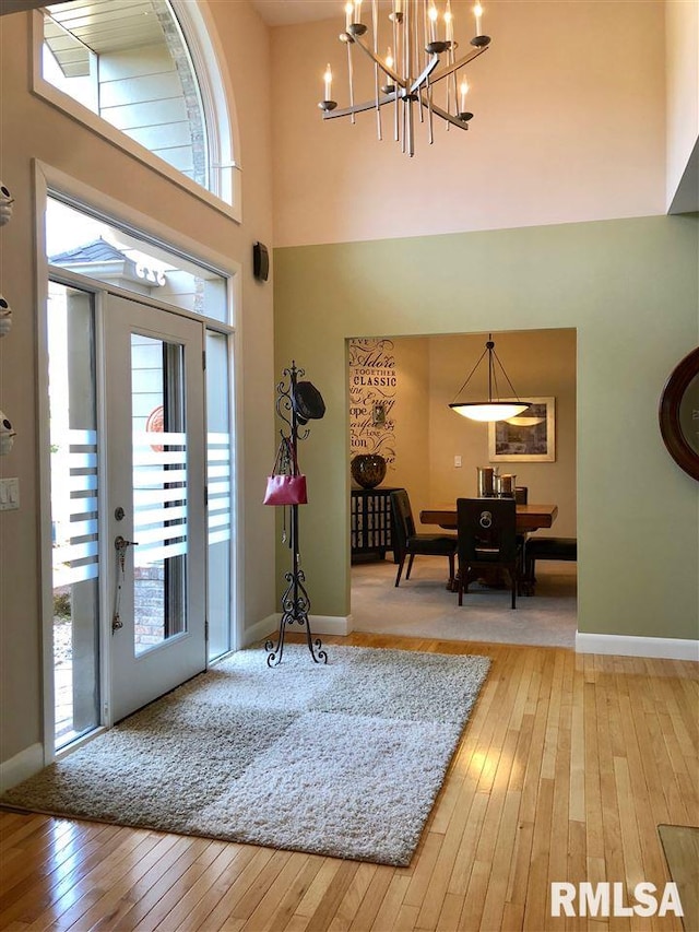 foyer entrance with wood-type flooring, a high ceiling, and an inviting chandelier