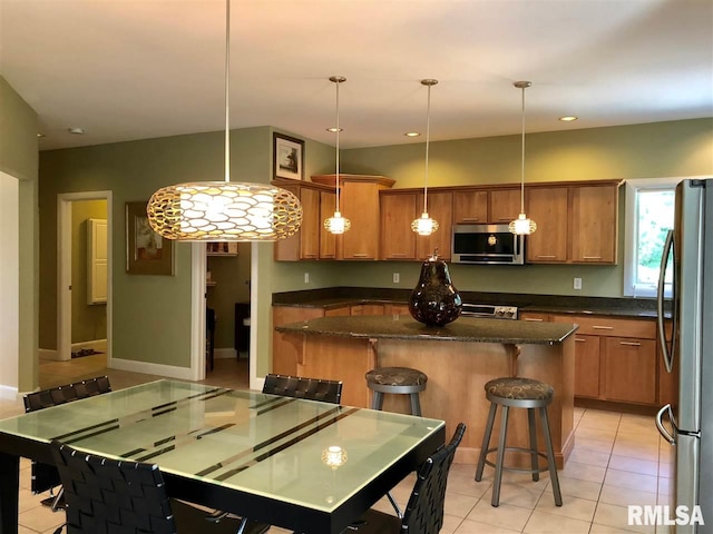 kitchen featuring pendant lighting, stainless steel appliances, a kitchen island, and a kitchen breakfast bar