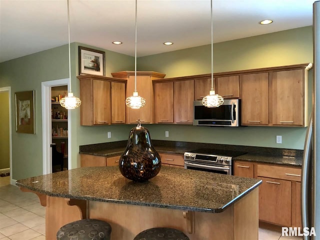 kitchen with a breakfast bar area, light tile patterned flooring, stainless steel appliances, and decorative light fixtures