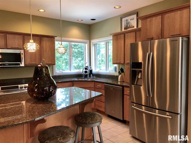 kitchen featuring appliances with stainless steel finishes, hanging light fixtures, dark stone counters, and sink