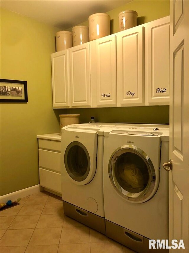 laundry area with cabinets, light tile patterned floors, and washing machine and clothes dryer