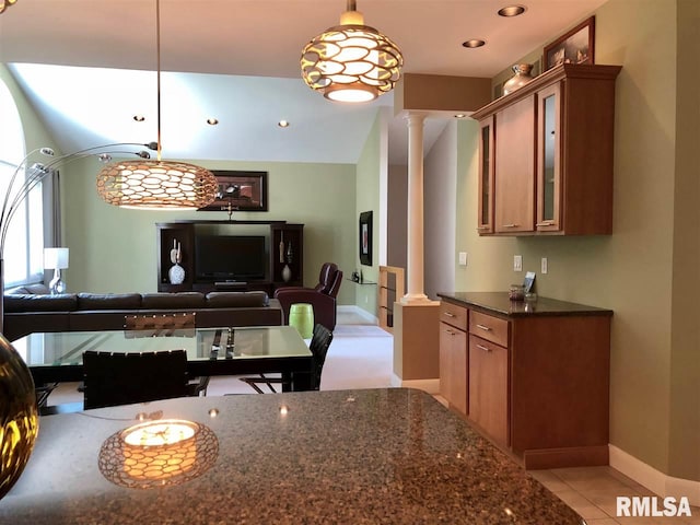 kitchen featuring light tile patterned flooring, decorative columns, hanging light fixtures, and dark stone countertops