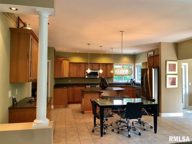 kitchen with pendant lighting, a center island, light tile patterned floors, appliances with stainless steel finishes, and decorative columns