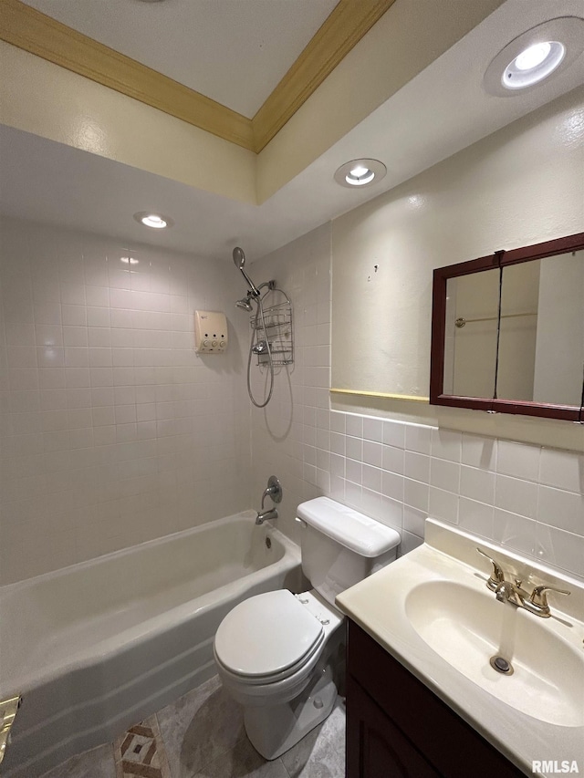 full bathroom with ornamental molding, vanity, tiled shower / bath combo, tile walls, and toilet