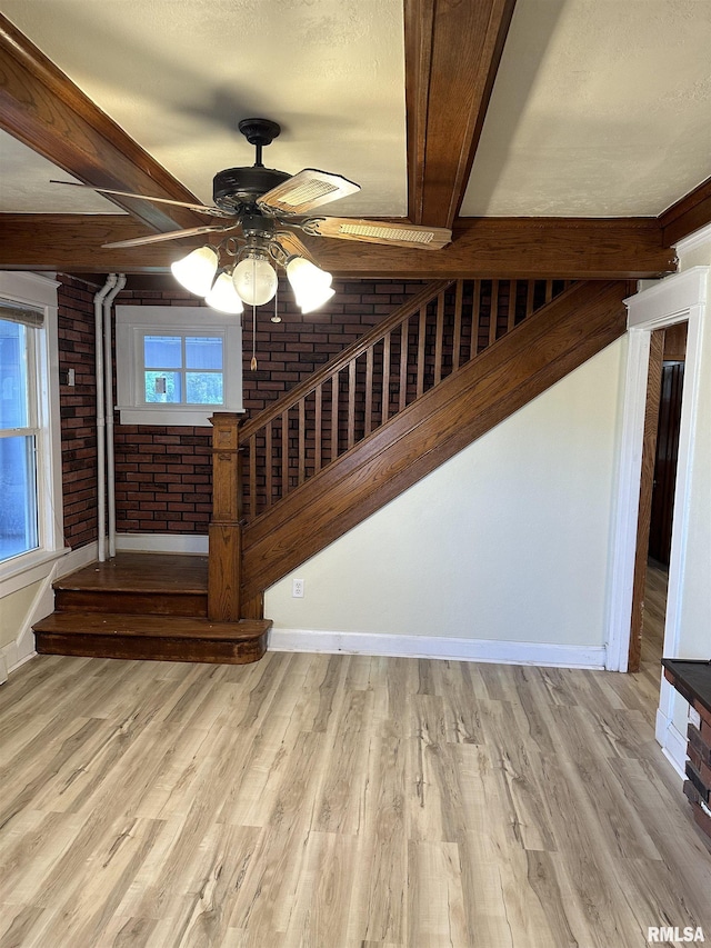 stairway featuring ceiling fan, wood-type flooring, and brick wall