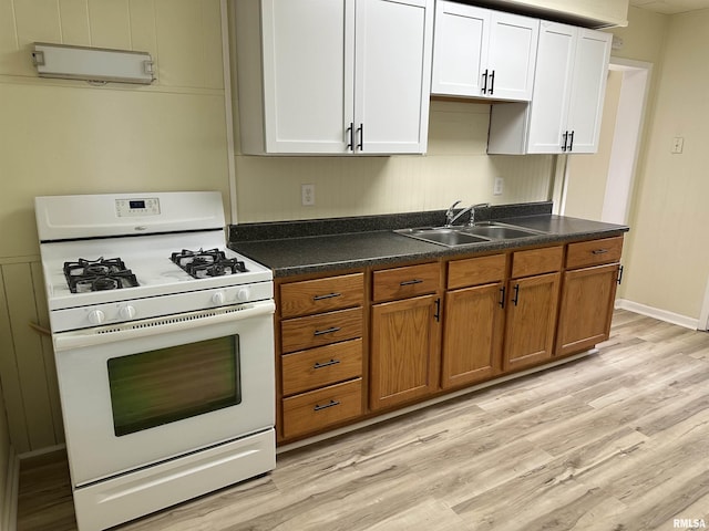 kitchen featuring white cabinetry, light wood-type flooring, white range with gas stovetop, and sink