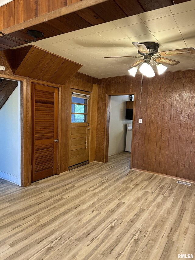 interior space featuring wooden walls, ceiling fan, and light wood-type flooring