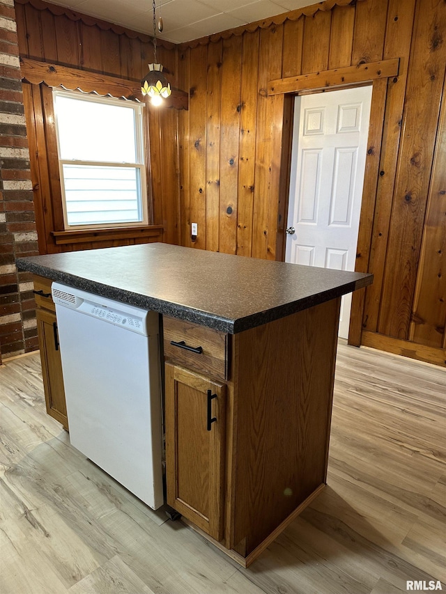 kitchen featuring wood walls, dishwasher, a center island, and pendant lighting